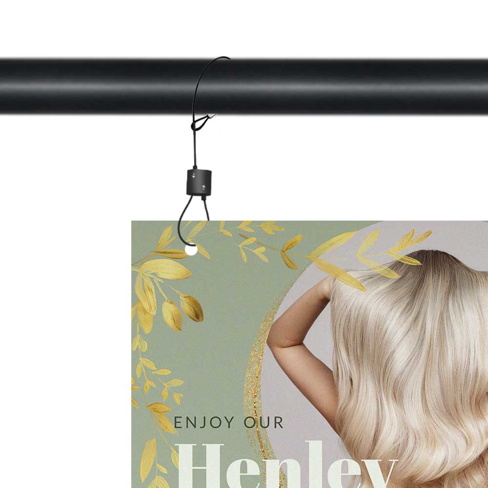 Image shows a the top left corner of a sign being hung via a black cable and urban trapeze from a pole. The sign shows a woman's blonde hair and reads 'enjoy our henley'.